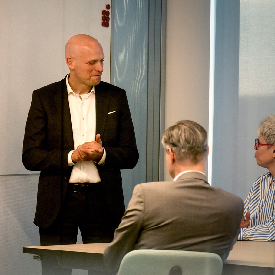 Ein Mann im Anzug steht vor einer Gruppe von Menschen